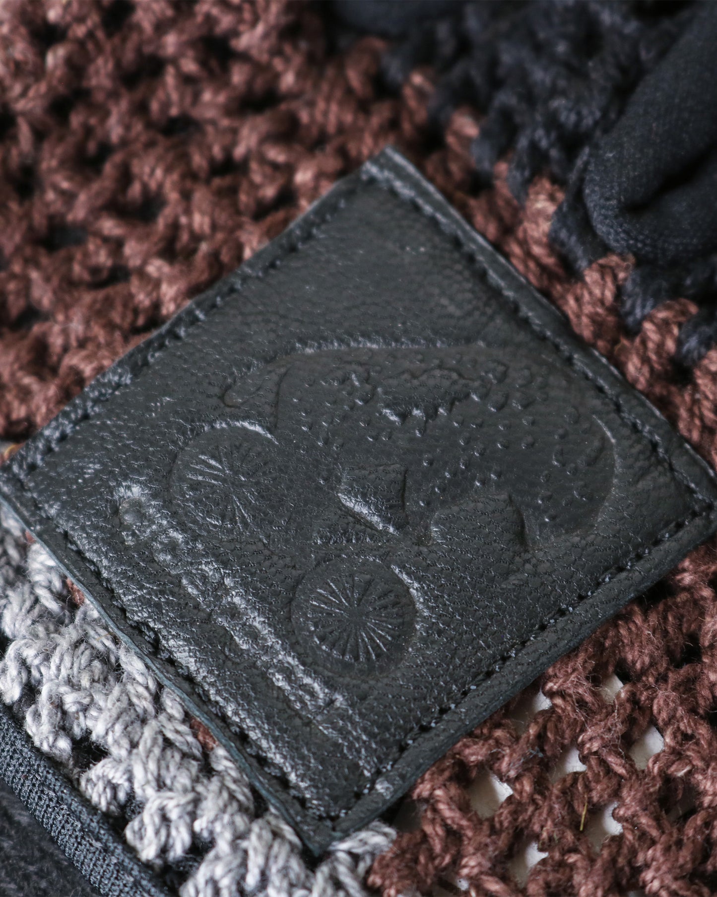 Padded, breathable mountain biking gloves made with goat leather and knitted yarn. Close up of bison embellishment